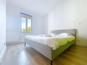 a bed in a white room with a window at Cocon lumineux à la porte de Paris in Gentilly