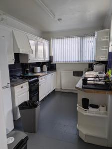 a kitchen with white cabinets and a trash can at Kettering Town End terrace walking distance to Kettering town in Kettering