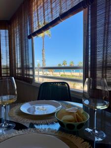 a table with a plate of bread and wine glasses at Beachfront apartment in El Altet