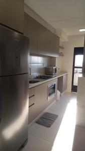 Una cocina con refrigerador de acero inoxidable y estufa. en Apto com piscina a 150m da Praia!, en Penha