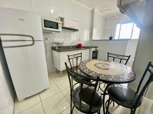 Una pequeña cocina con una mesa y un refrigerador. en Residencial Maria Conceição, en Samaritá