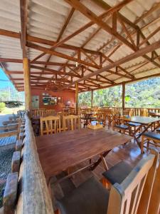 a restaurant with a large wooden table and chairs at Cabanas V 13, 2ª maior viaduto do mundo! Camping in Vespasiano Corrêa