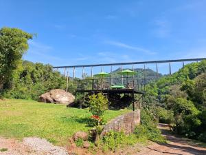 a bridge with green umbrellas on top of a field at Cabanas V 13, 2ª maior viaduto do mundo! Camping in Vespasiano Corrêa +13 photos