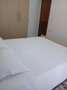 a large white bed in a room with a closet at Aila Apartament in Gjirokastër +5 photos