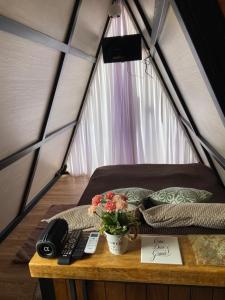 a bed in a tent with a phone and flowers on a table at Mini Cabana Makar in Serra do Cipo