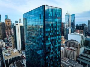 a tall glass building in a large city at Novotel Melbourne Central in Melbourne
