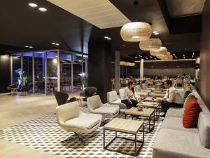 a lobby with people sitting at tables and chairs at Novotel Santiago Providencia in Santiago