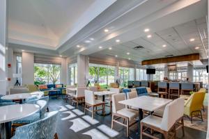 a restaurant with tables and chairs and windows at Hilton Garden Inn Louisville Airport in Louisville