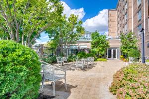 a row of chairs on a brick patio in front of a building at Hilton Garden Inn Louisville Airport in Louisville