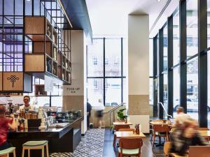 a restaurant with large windows and people walking through it at Novotel Melbourne Central in Melbourne