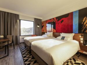 a hotel room with two beds and a desk at Novotel Santiago Providencia in Santiago +84 photos