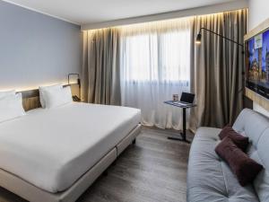 a hotel room with a large bed and a couch at Novotel Parma Centro in Parma