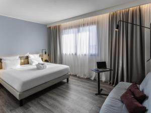 a hotel room with a bed and a laptop on a table at Novotel Parma Centro in Parma +165 photos