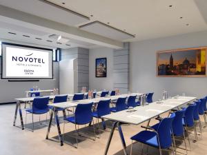 パルマにあるNovotel Parma Centroのテーブルと椅子、プロジェクションスクリーンが備わる客室です。