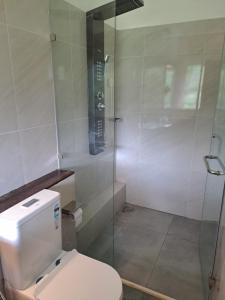 a bathroom with a toilet and a glass shower at Alankara Nature Resort in Kitulgala