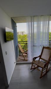 a room with a balcony with two chairs and a television at Apartamento acogedor en Santa Marta in Santa Marta