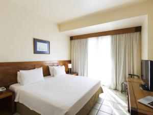 a bedroom with a large white bed and a window at Novotel Salvador Rio Vermelho in Salvador