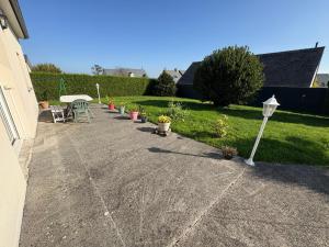 a patio with a table and chairs and plants at Maison tout confort près du Mont-Saint-Michel in Saint-Quentin-sur-le-Homme +2 photos