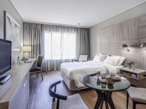 a hotel room with a large bed and a table at Pullman Santiago Vitacura in Santiago +169 photos