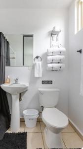 een witte badkamer met een toilet en een wastafel bij Isla Bonita Townhouse - 5 min SJU in Carolina