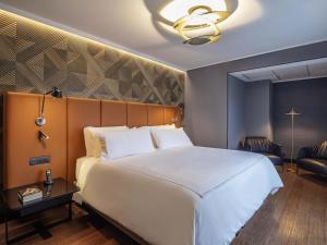 a bedroom with a large white bed and a chair at Pullman Santiago Vitacura in Santiago