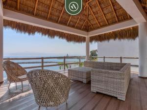 a patio with chairs and tables and a view of the ocean at Luxury Oceanfront 3 BR Condo with Balcony in Cruz de Huanacaxtle