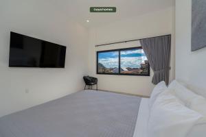 a bedroom with a bed and a flat screen tv at Amazing Apt with City View - Rooftop Pool in Los Médanos Partidos +21 photos