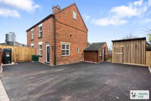 un gran edificio de ladrillo con aparcamiento en Pear Tree Cottage Pool Table 15mins drive to Alton Towers, en Denstone