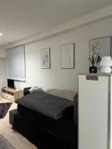 a bedroom with a black bed and a white wall at Gemütliches, barrierefreies Apartment in Dortmund-Brackel, Ruhige Lage, nur 5 Minuten zum Flughafen Dortmund in Dortmund