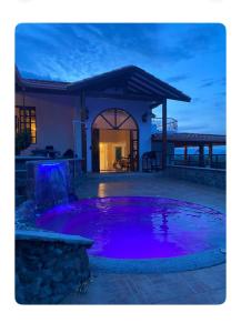 een huis met een grote vijver met paars water bij Finca Hotel Gudys in Estación Belmonte