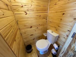 a small bathroom with a toilet and wooden walls at Pousada e Camping do Motochileiro in Urubici