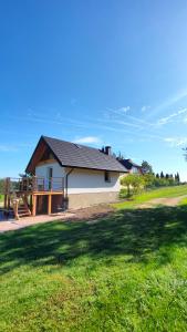 una casa con techo negro en un campo verde en Domek Czarnucha, en Augustów