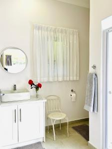a white bathroom with a sink and a mirror at Autumn Way in Clarens