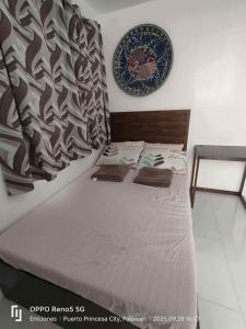 een bed in een kamer met een bord aan de muur bij Serene Home Stay in Puerto Princesa City