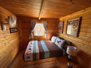 a bedroom in a log cabin with a bed in it at Katie's Cozy Cabins in Tombstone