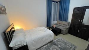 a small bedroom with a bed and a chair at XD Cozy Apartments in Abu Dhabi