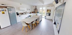 eine Küche mit einem Holztisch und weißen Geräten in der Unterkunft Villa Émeraude in Vic-la-Gardiole