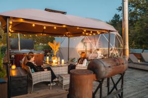 two women sitting at a restaurant under an umbrella at Romantic Dome - Private Hot Tube, Sauna & Lake view in Wapnica +22 photos