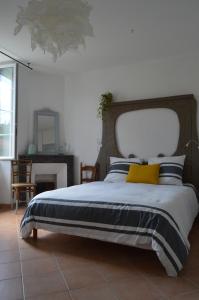 1 dormitorio con 1 cama grande con almohada amarilla en Le Moulin de Bassac, en Bassac