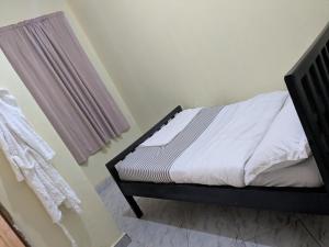 a bedroom with a bed with white sheets and a window at Masaka Haven in Masaka
