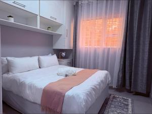 a bedroom with a large white bed and a window at Windermere Sands in Gqeberha