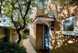 una casa de ladrillo con una puerta azul y un árbol en New Forest home - 4-beds and garden - 10 mins from Beach, en Hordle