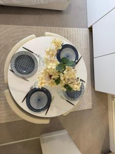 Una mesa blanca con dos platos y flores. en Studio moderne et sécurisé, en Compiègne