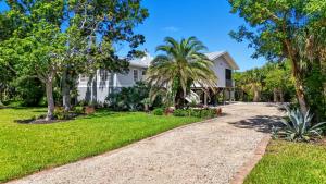 a house with palm trees and a gravel driveway at Your Island Oasis Awaits on Sanibel - Near Beach in James Cipriani Heliport