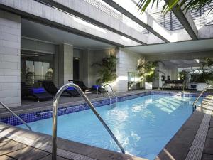 a swimming pool in a building with a building at Pullman Santiago El Bosque in Santiago
