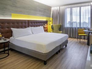 a bedroom with a large bed in a room with chairs at Pullman Santiago El Bosque in Santiago