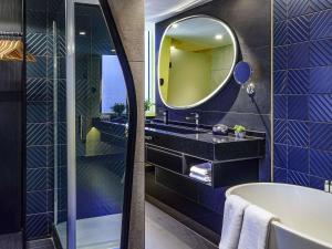 ein Badezimmer mit Badewanne und Spiegel in der Unterkunft Pullman Santiago El Bosque in Santiago + 150 Fotos
