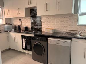 a kitchen with a washer and dryer in it at Windermere Sands in Gqeberha