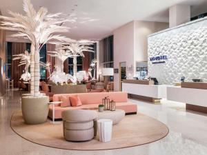 a lobby with a pink couch and palm trees at Novotel Miami Brickell in Miami