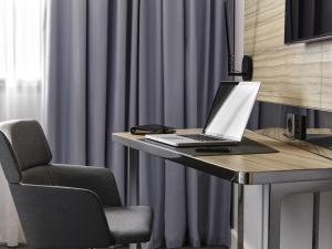 a laptop computer sitting on a desk with a chair at Novotel Saint-Étienne Centre Gare Châteaucreux in Saint-Étienne